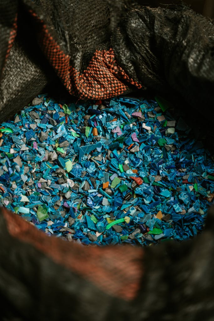 Detailed close-up of colorful recycled plastic fragments in a black sack, showcasing sustainability.